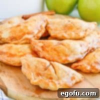 Close up of finished glazed Air Fryer Apple Hand Pies on wooden board.