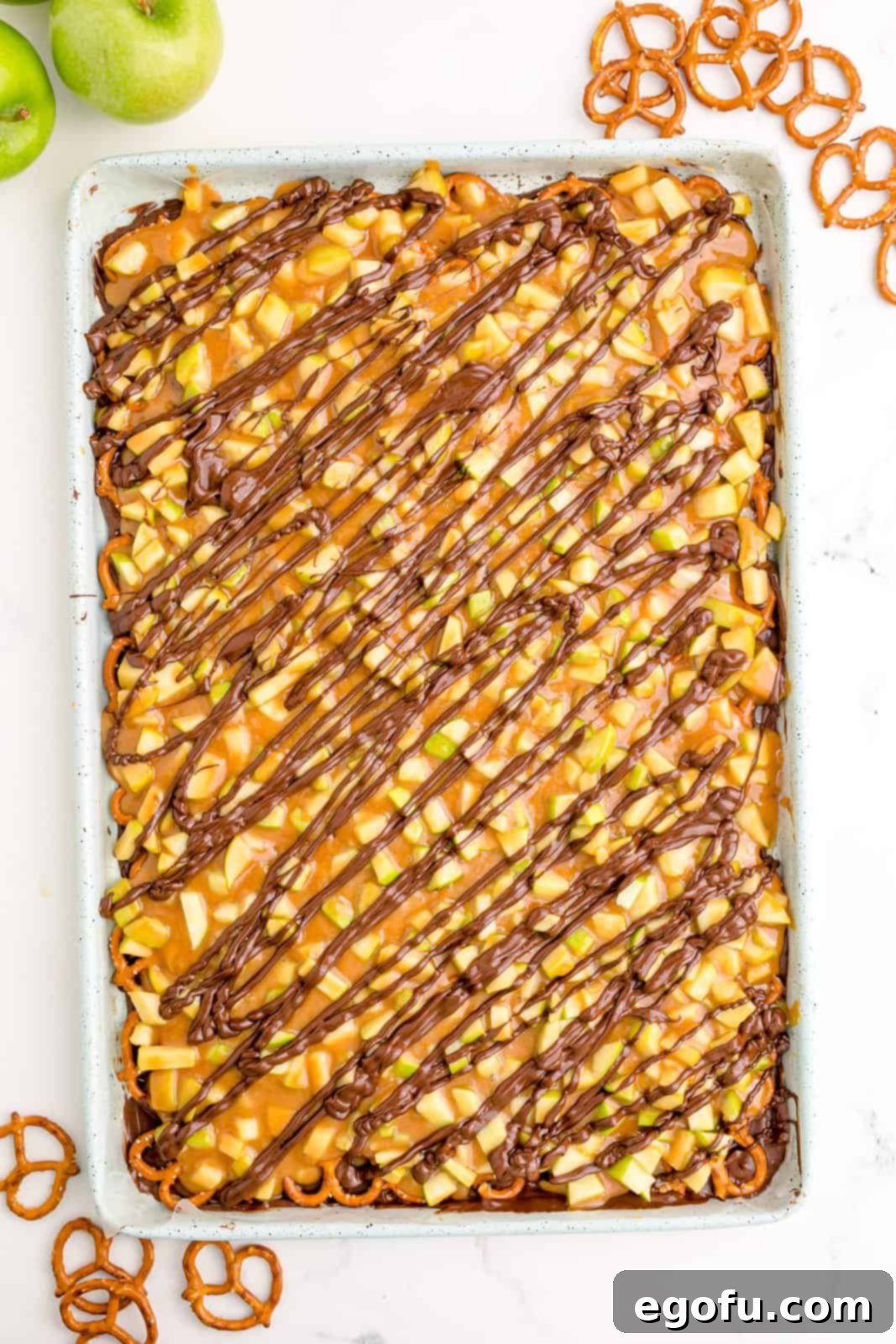 A final drizzle of melted chocolate over the set caramel apple bark, adding a decorative touch.