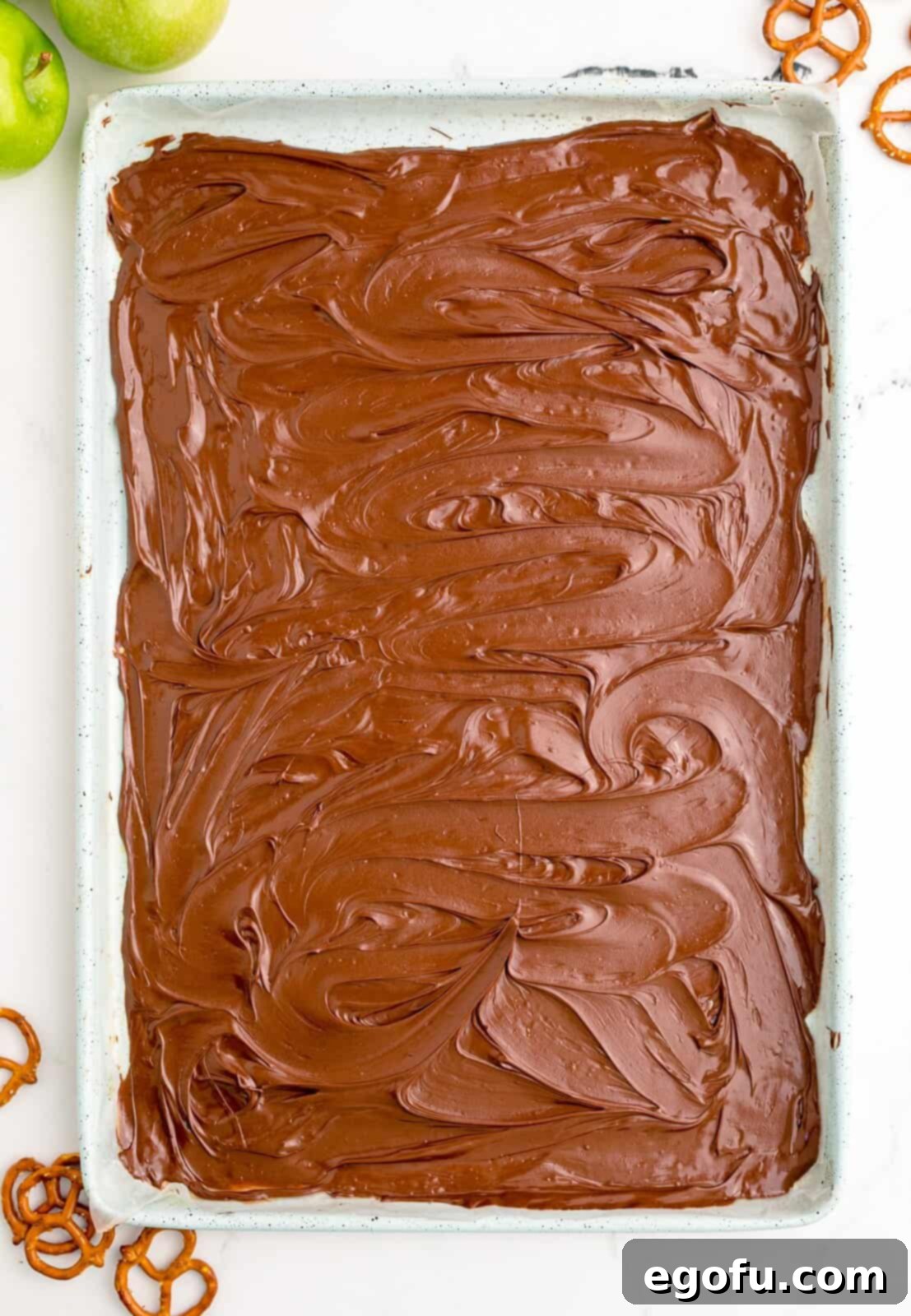 Melted chocolate smoothly spread over a parchment-lined baking sheet.