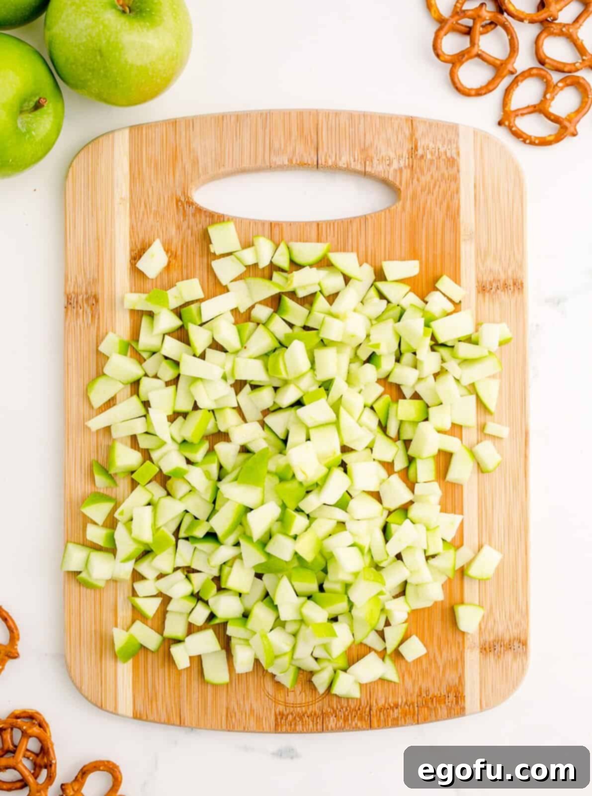 Freshly diced apples on a wooden cutting board, ready for the next step.