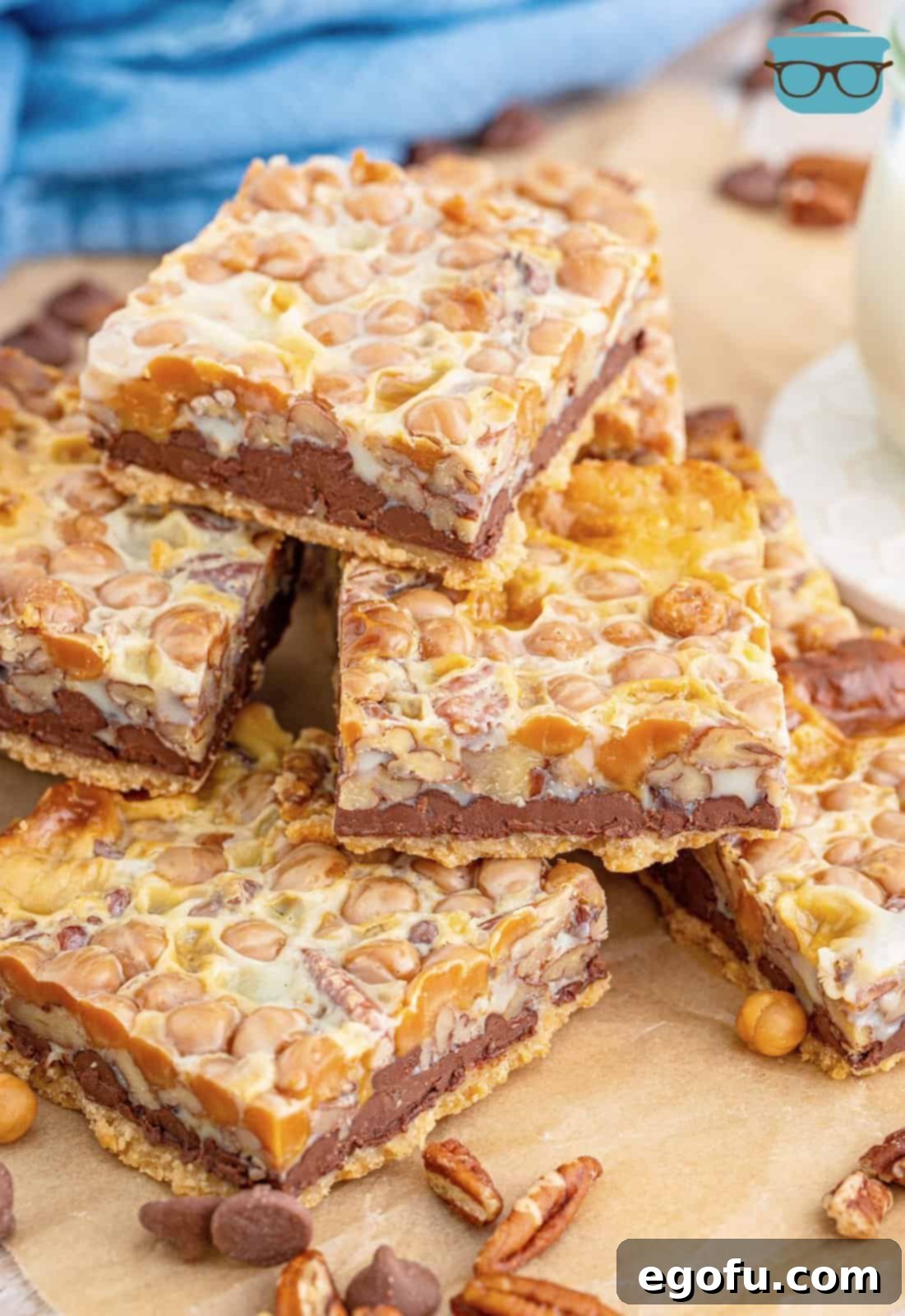 Stacked Turtle Magic Bars on wooden board, showcasing the layers of chocolate, caramel, and pecans.