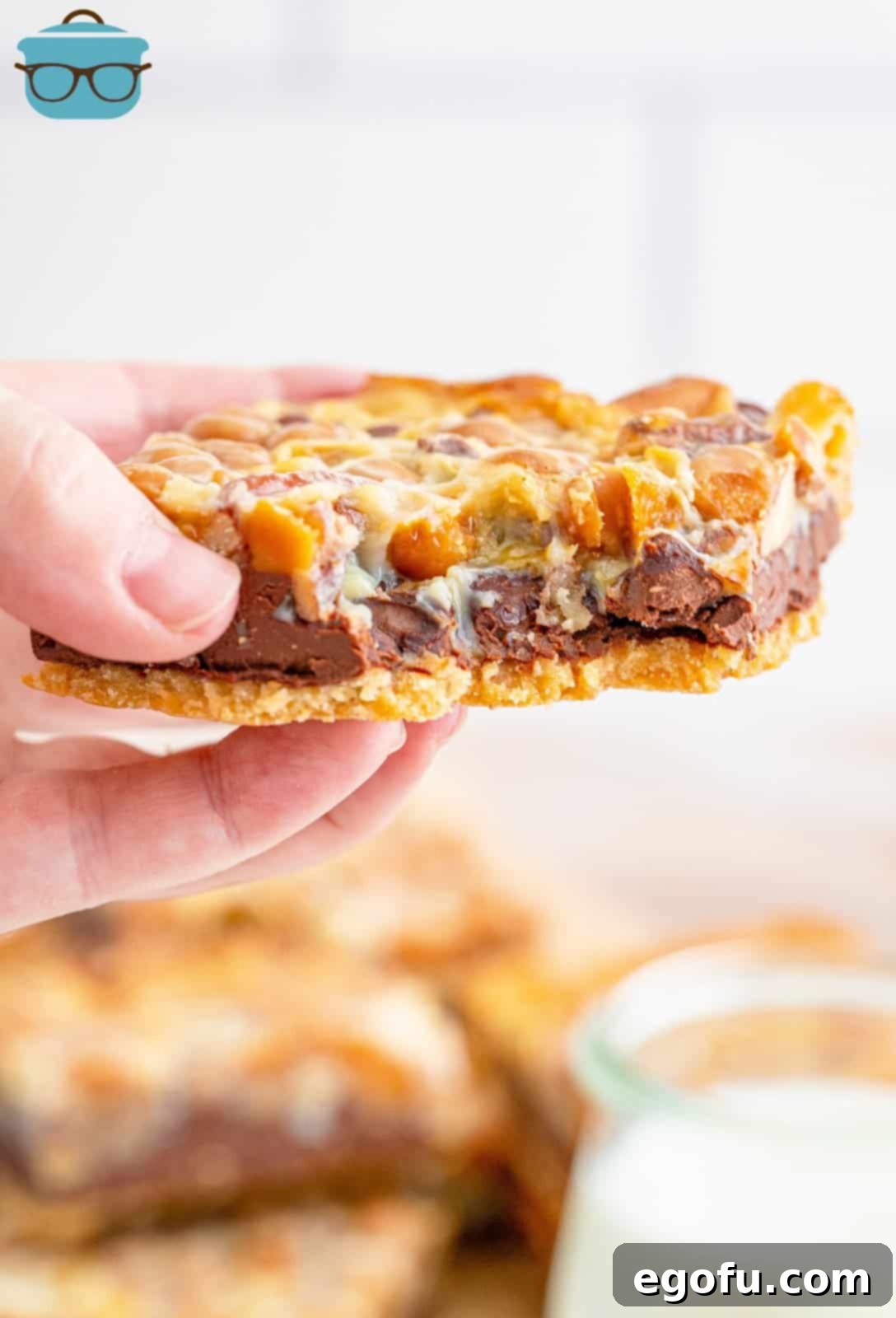 A hand holding one Turtle Magic Bar with a bite taken out of it, showing the gooey center and crispy edges.
