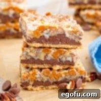 Square image of three stacked Turtle Magic Bars with chocolate chips and nuts.