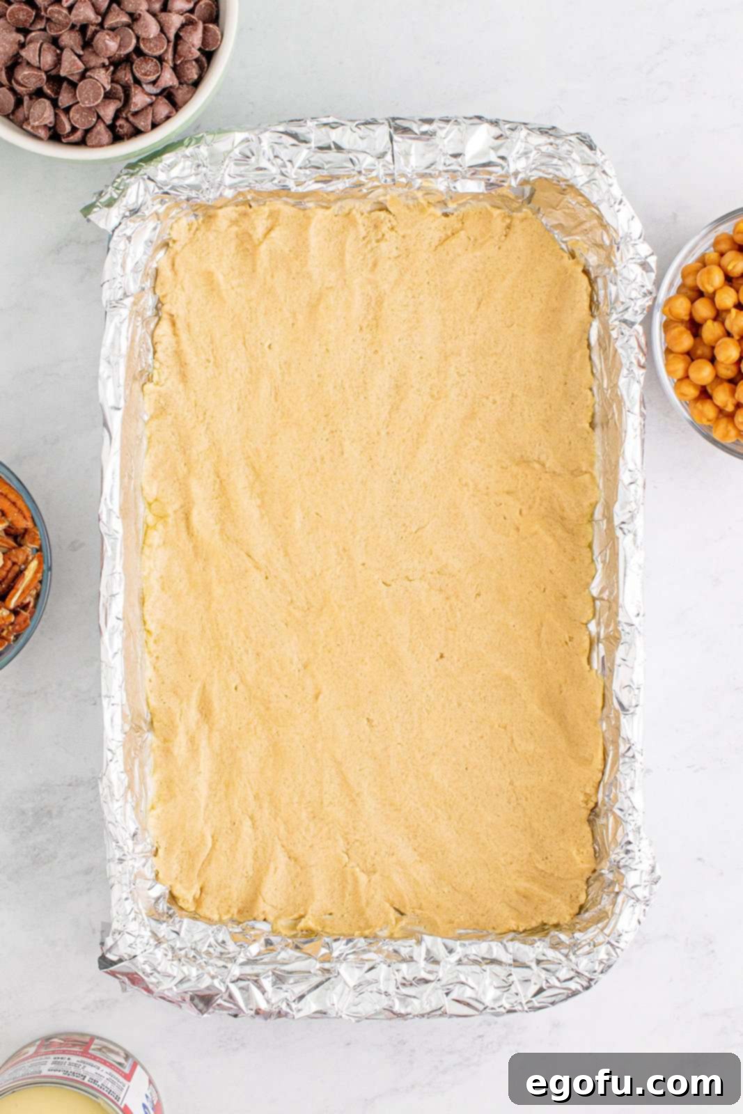 The dough pressed firmly and evenly into the bottom of the prepared baking pan, forming the crust.