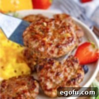 Close up square image of Homemade Breakfast Sausage held up by metal spatula with plate in background.