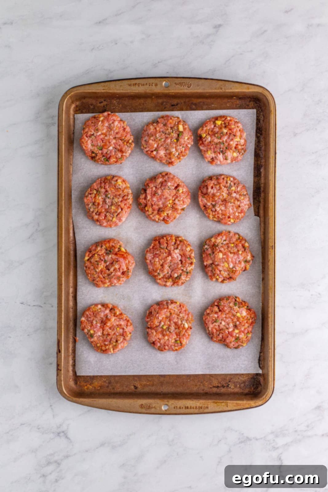 Sausage patties on parchment lined baking sheet.