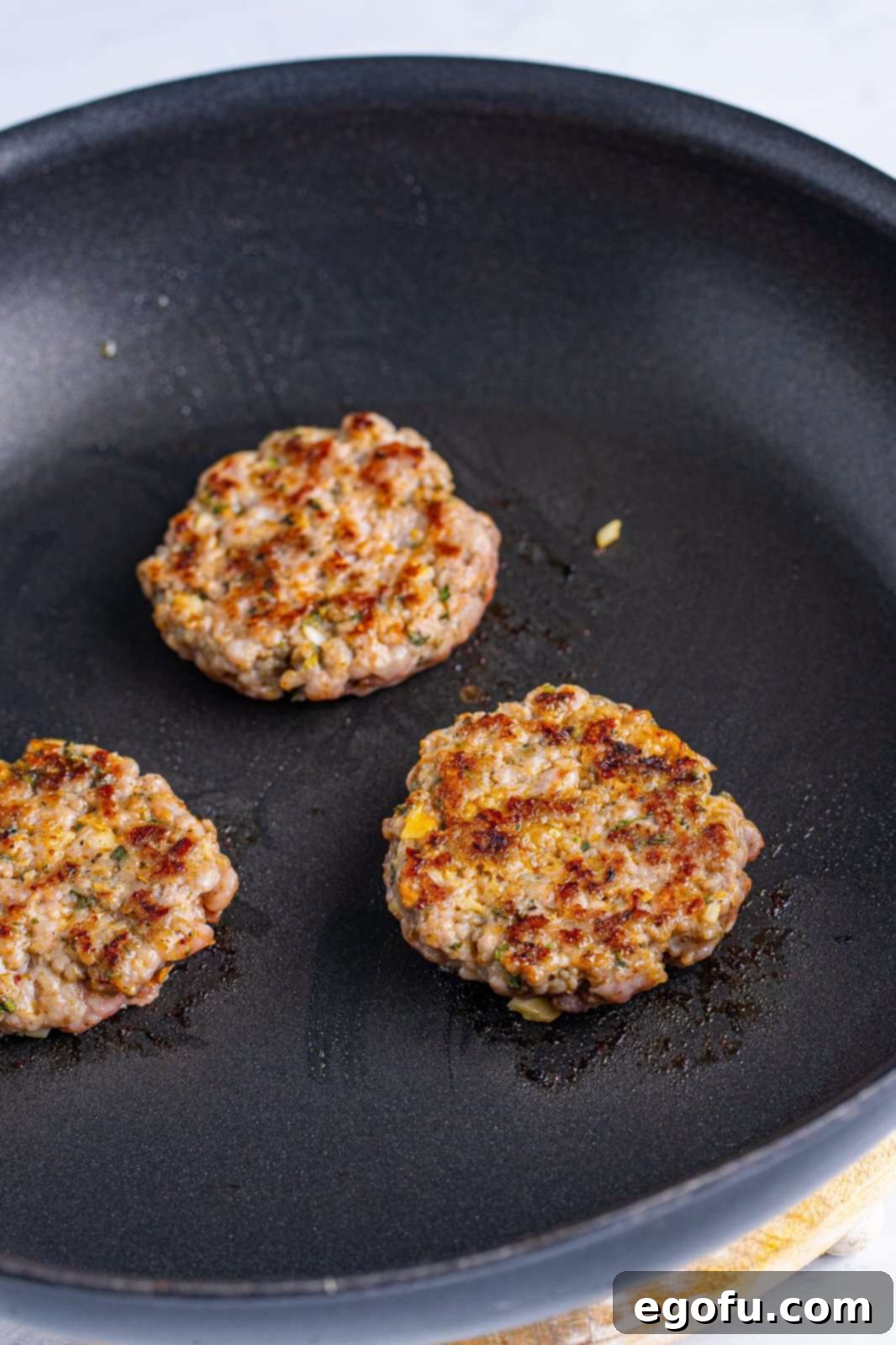 Sausage patties being browned in pan.