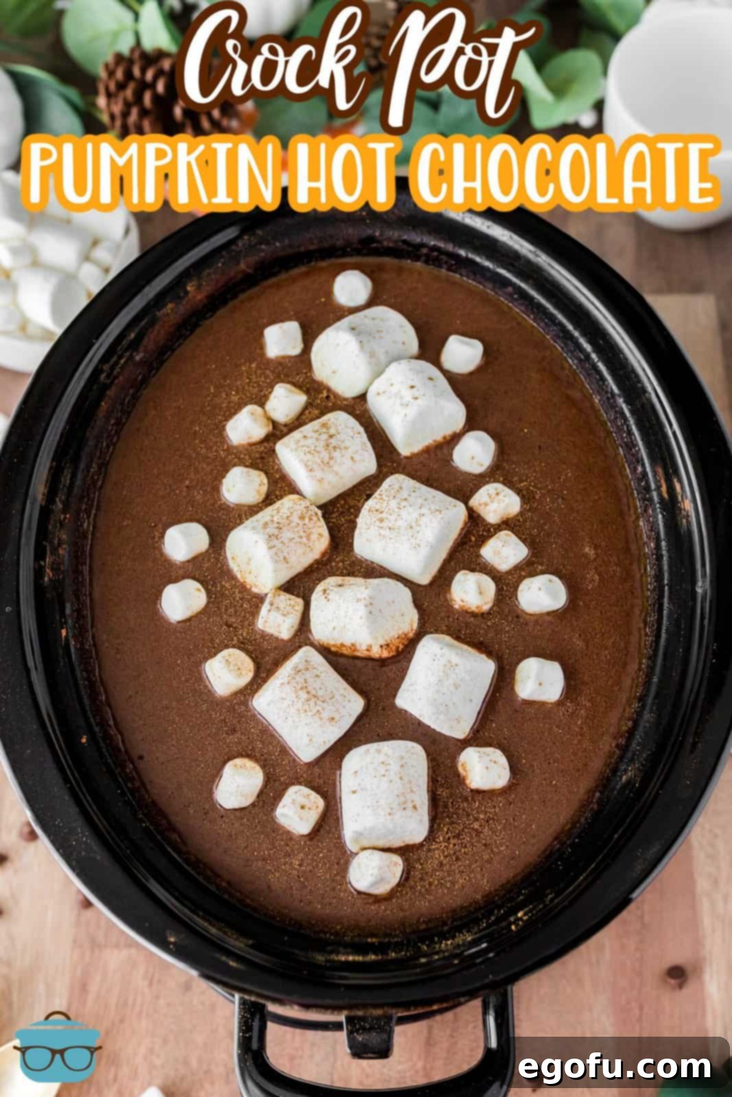 A slow cooker filled with creamy pumpkin hot chocolate, topped with a generous amount of fluffy marshmallows, ready to be served.