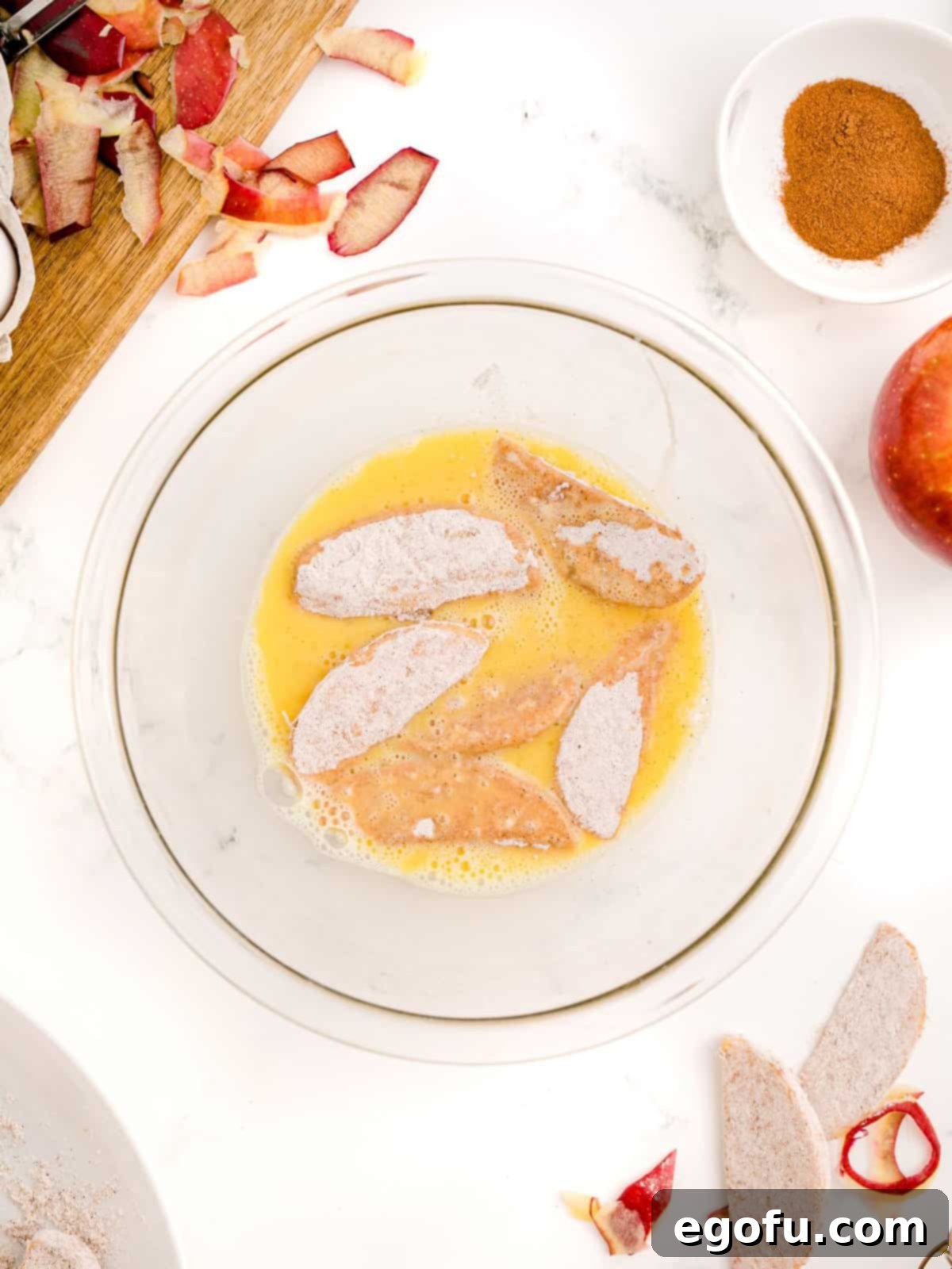 Flour covered apples placed in egg mixture.