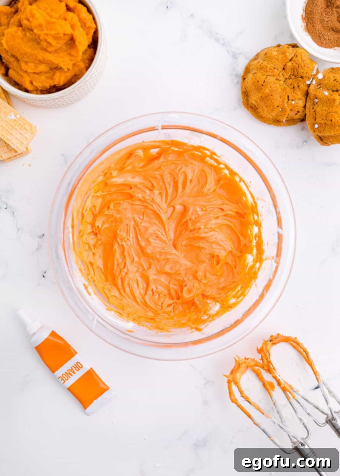 Cream cheese frosting in bowl with orange food coloring.