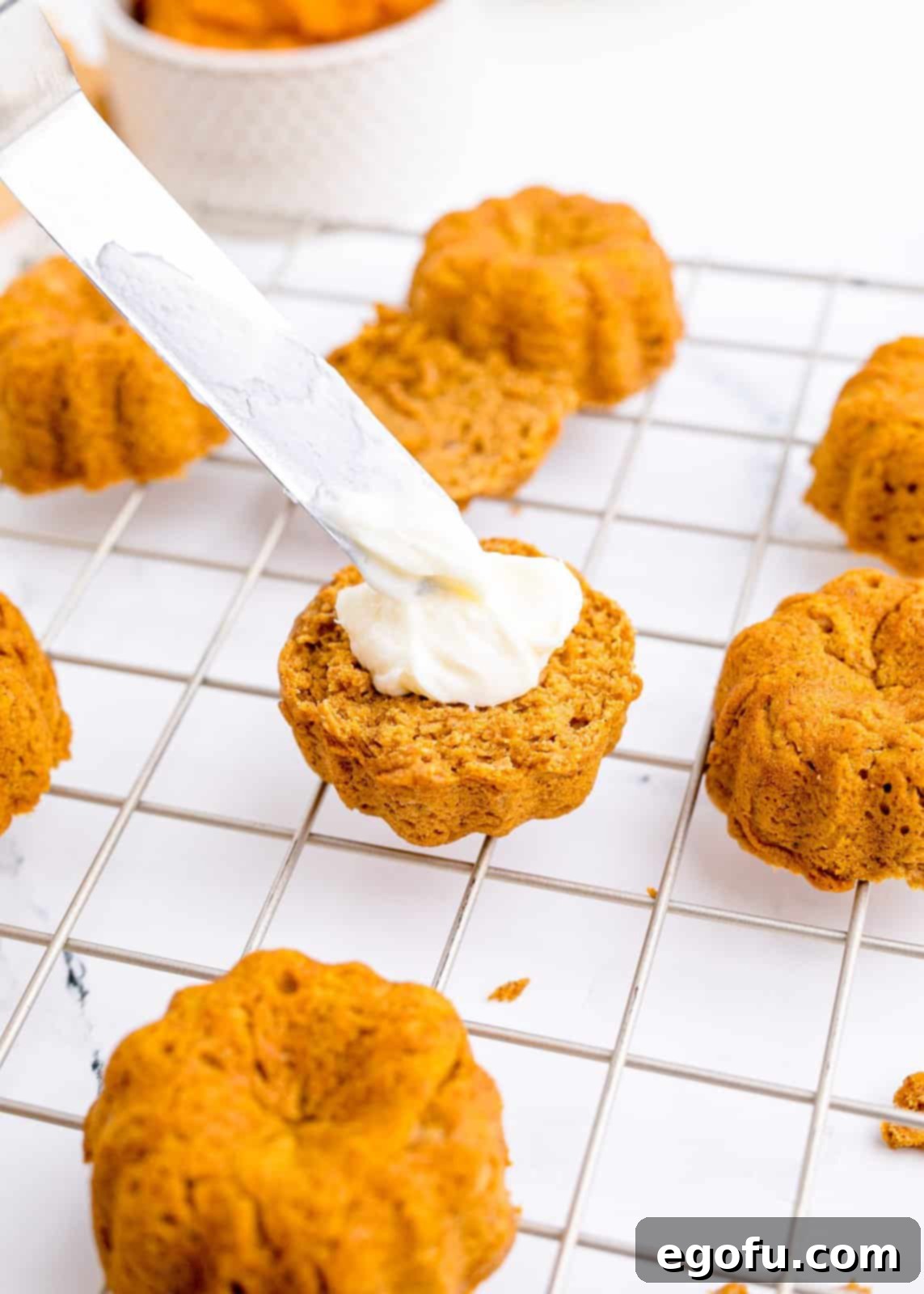 Bottom of cakes being spread with the white cream cheese frosting.