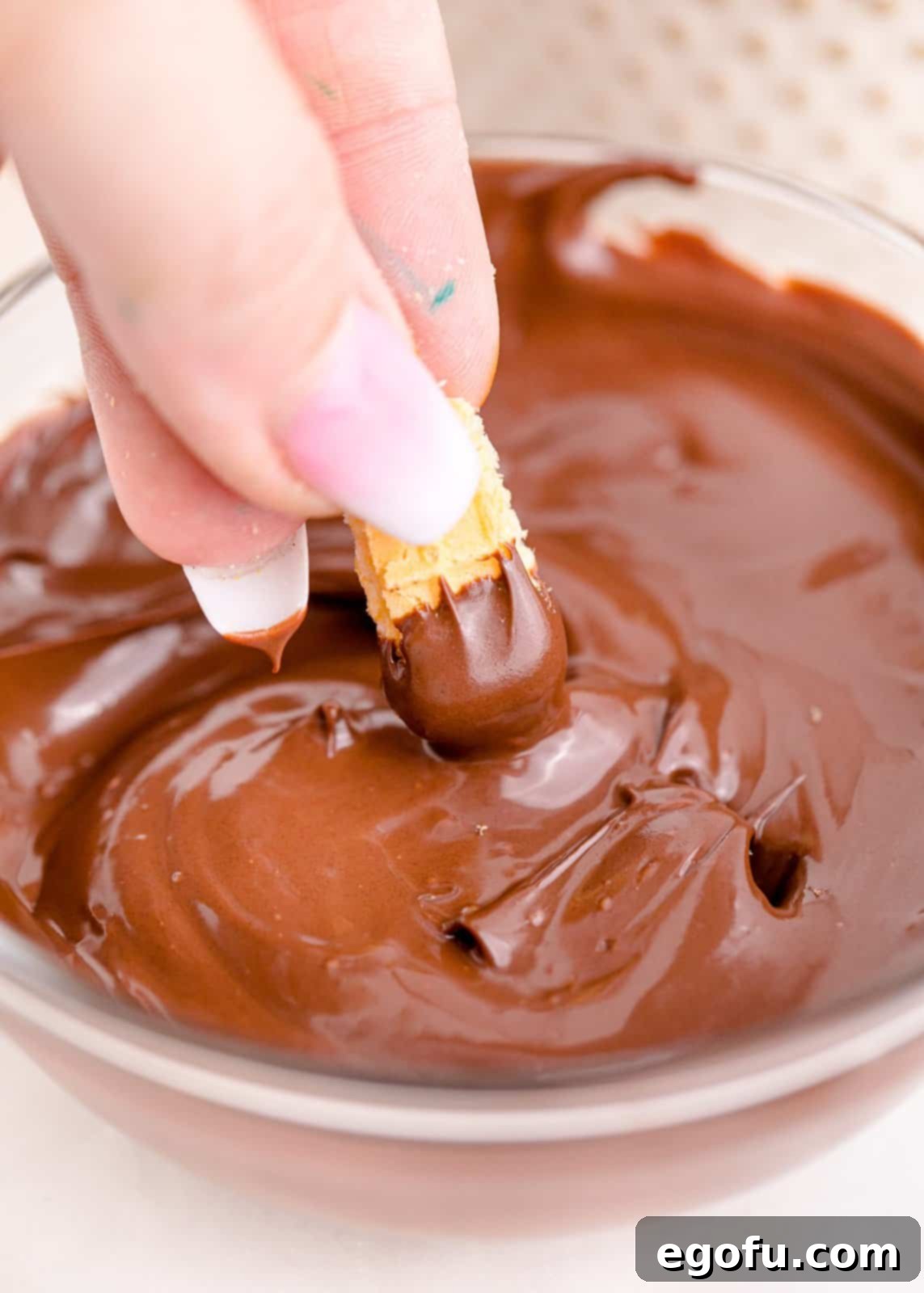 Melted chocolate with wafer cookie being dipped into it.