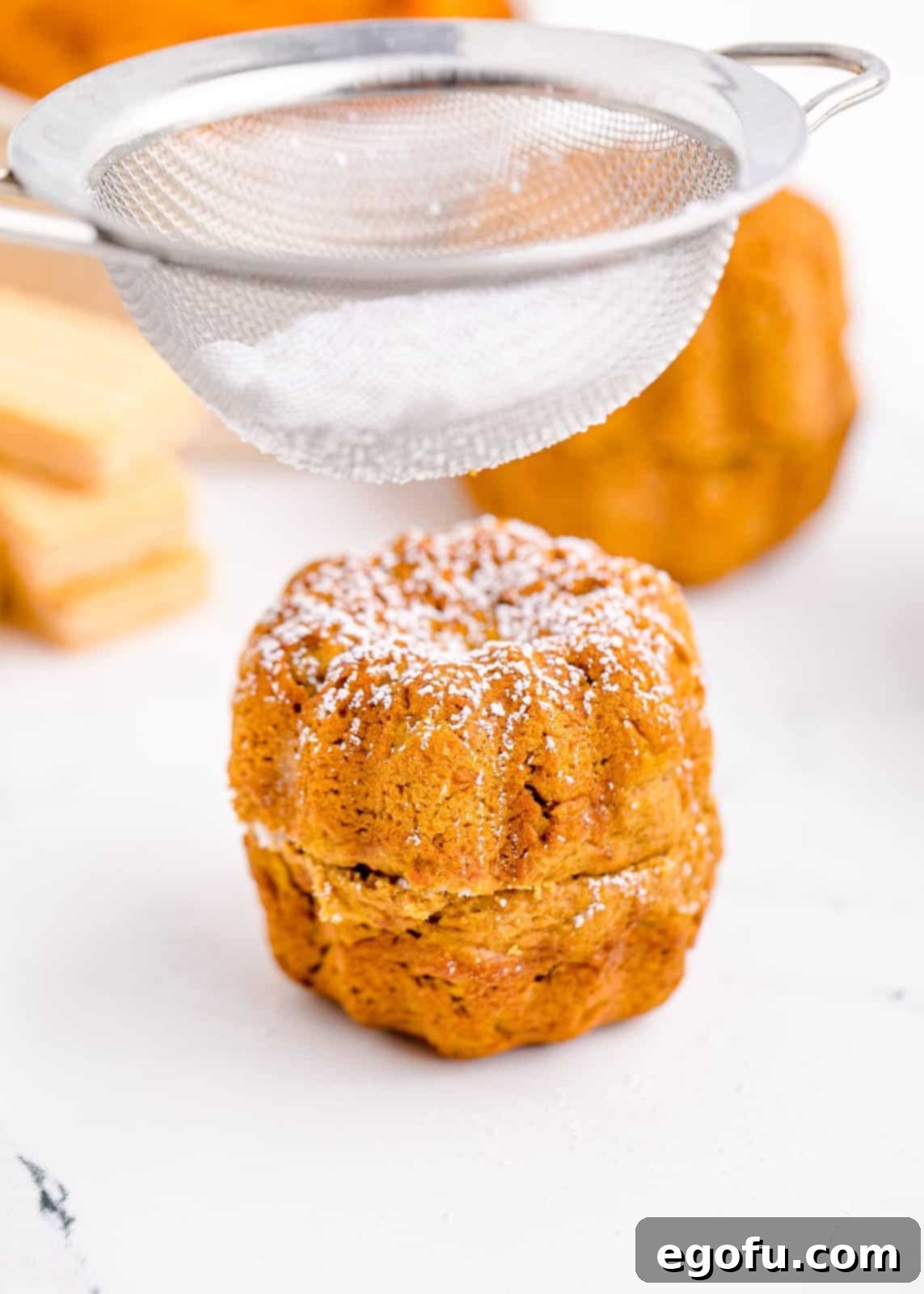 Mini bundt cake being sifted with powdered sugar.