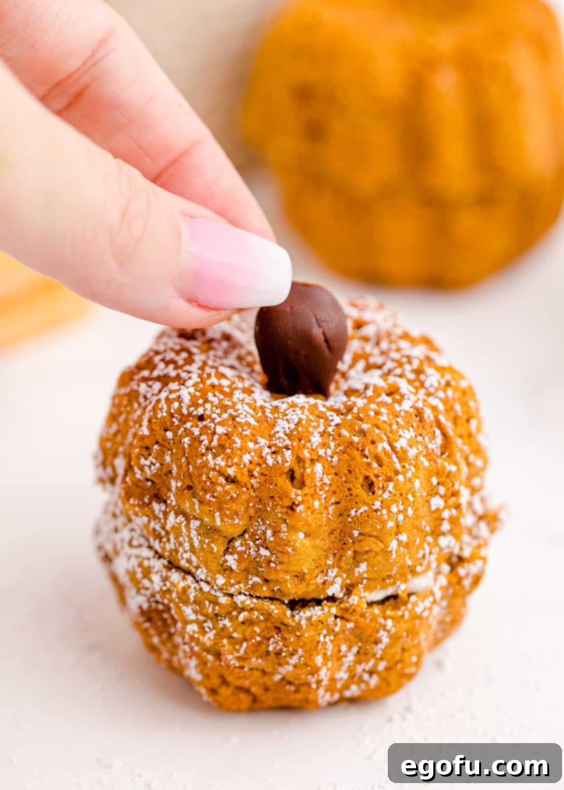 Hand placing chocolate covered wafer on top of the bundt cake.