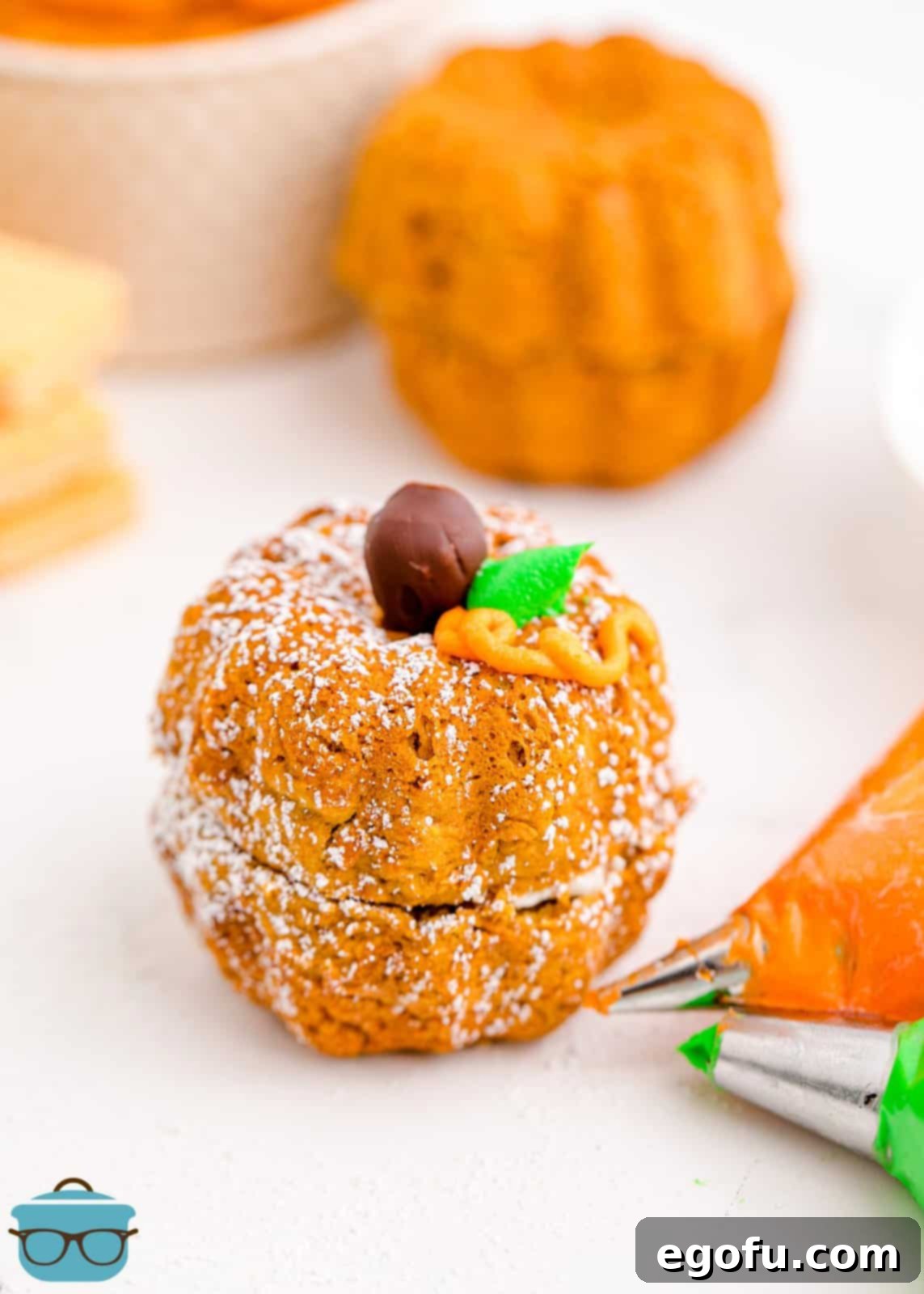 Finished decorated Mini Pumpkin Bundt Cakes on white board with piping bags.
