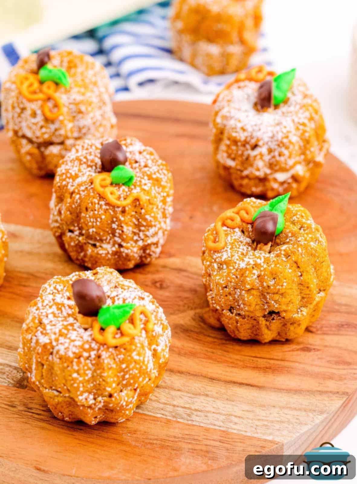 Multiple Mini Pumpkin Bundt Cakes on wooden board decorated.