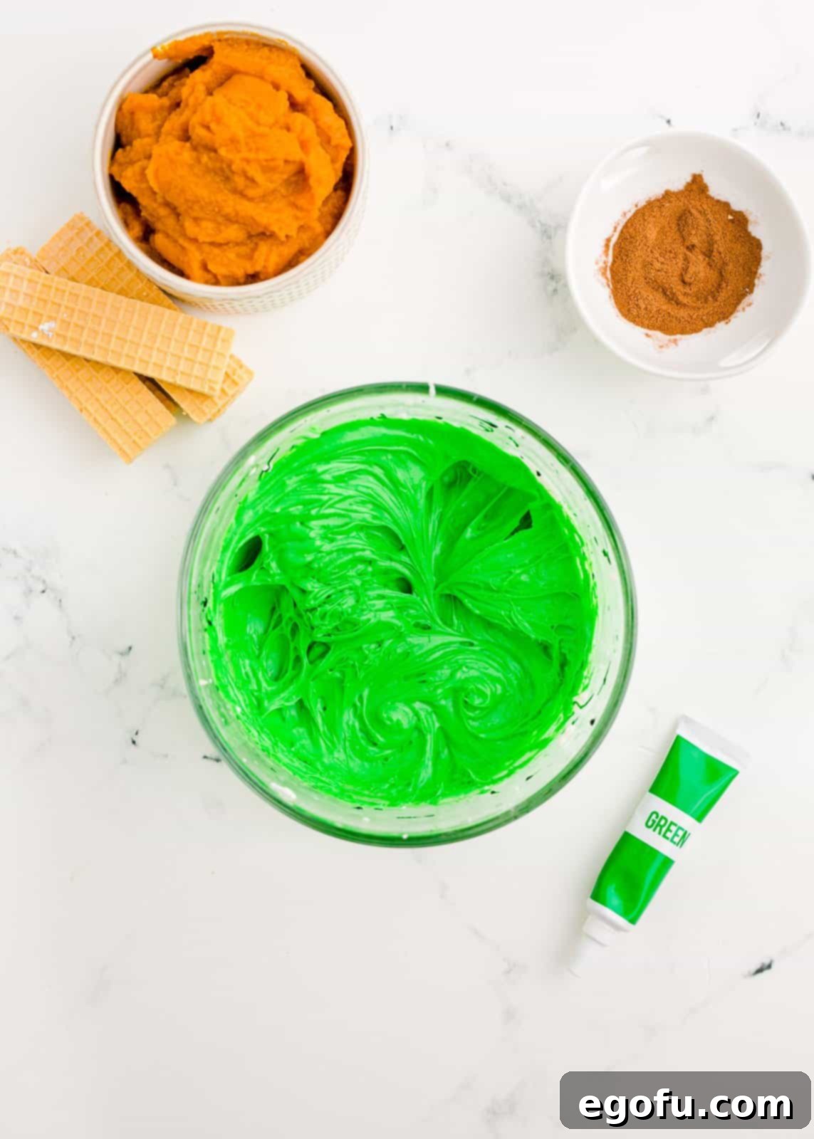 Cream cheese frosting in bowl with green food coloring.