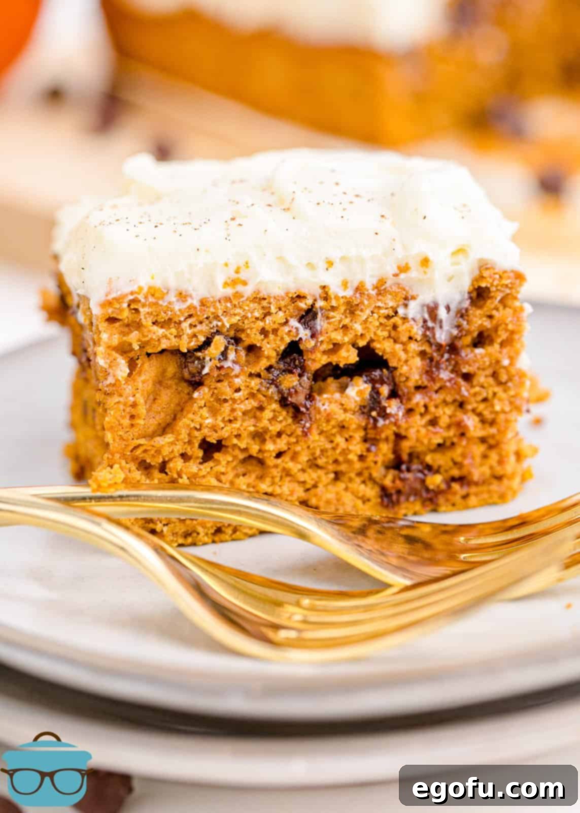 Slice of Pumpkin Chocolate Chip Cake on white plat with gold forks.