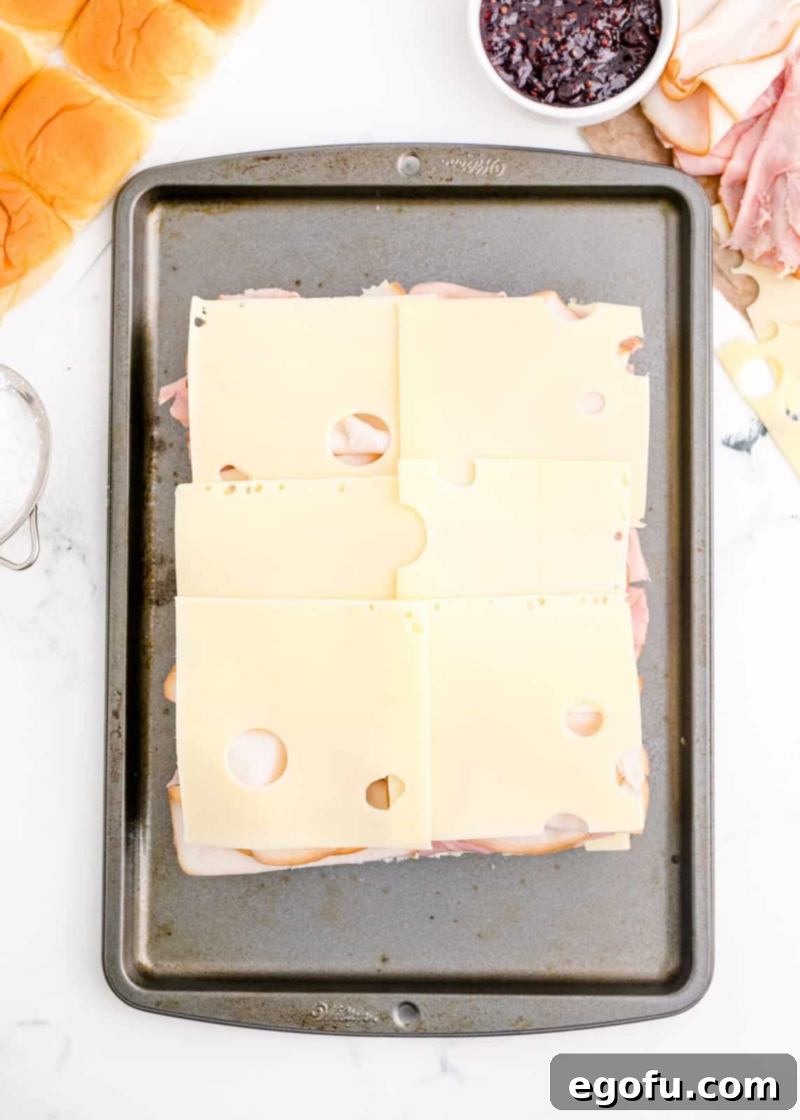 Layered cheese and meats on top of rolls.