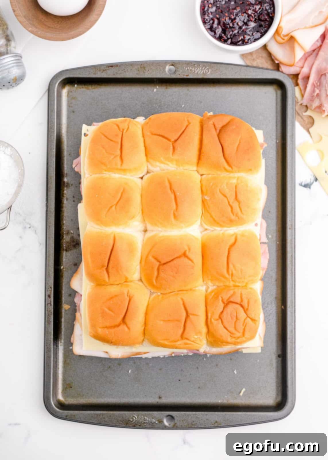 Tops of rolls placed on filling ingredients.
