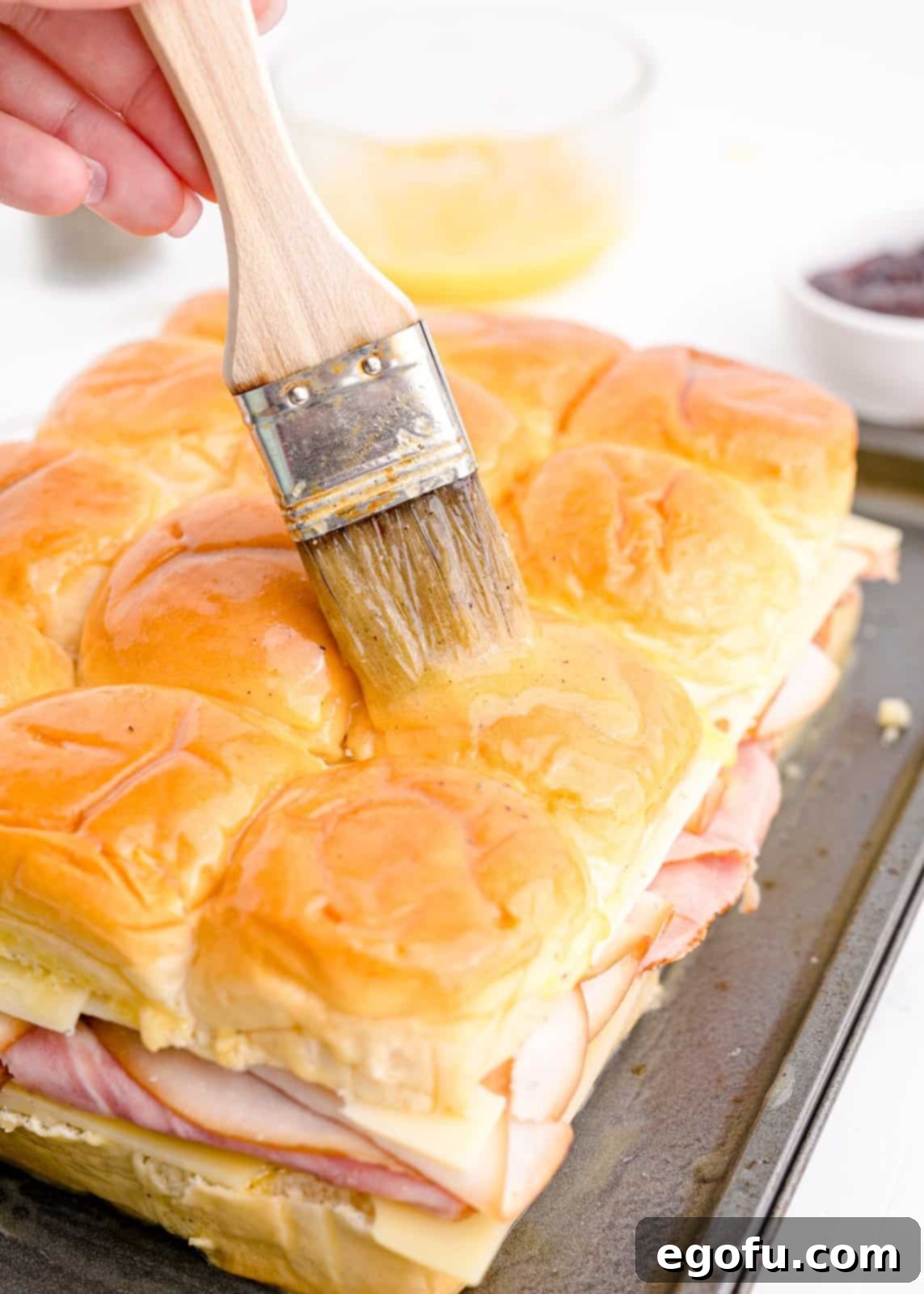 Butter mixture being brushed over tops of rolls.