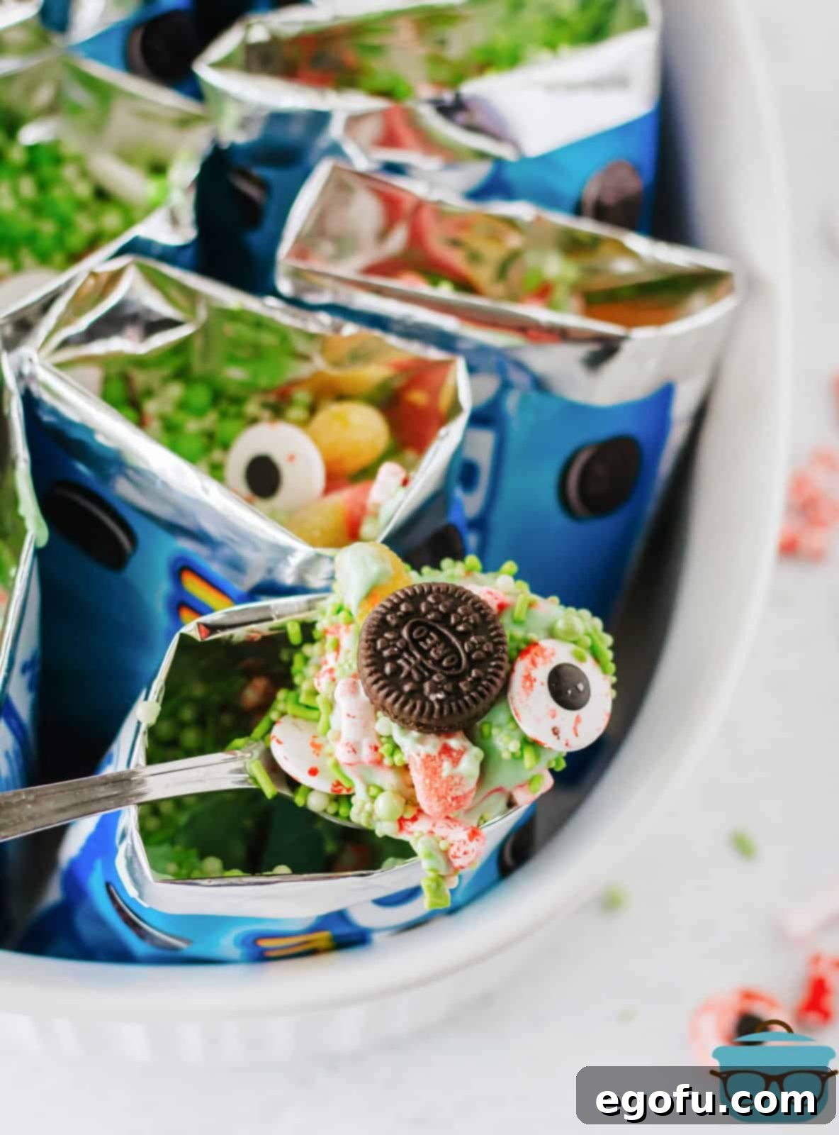 A spoon lifting a portion of the Witches Brew from a snack bag, revealing the layers of cookies, pudding, and candies.