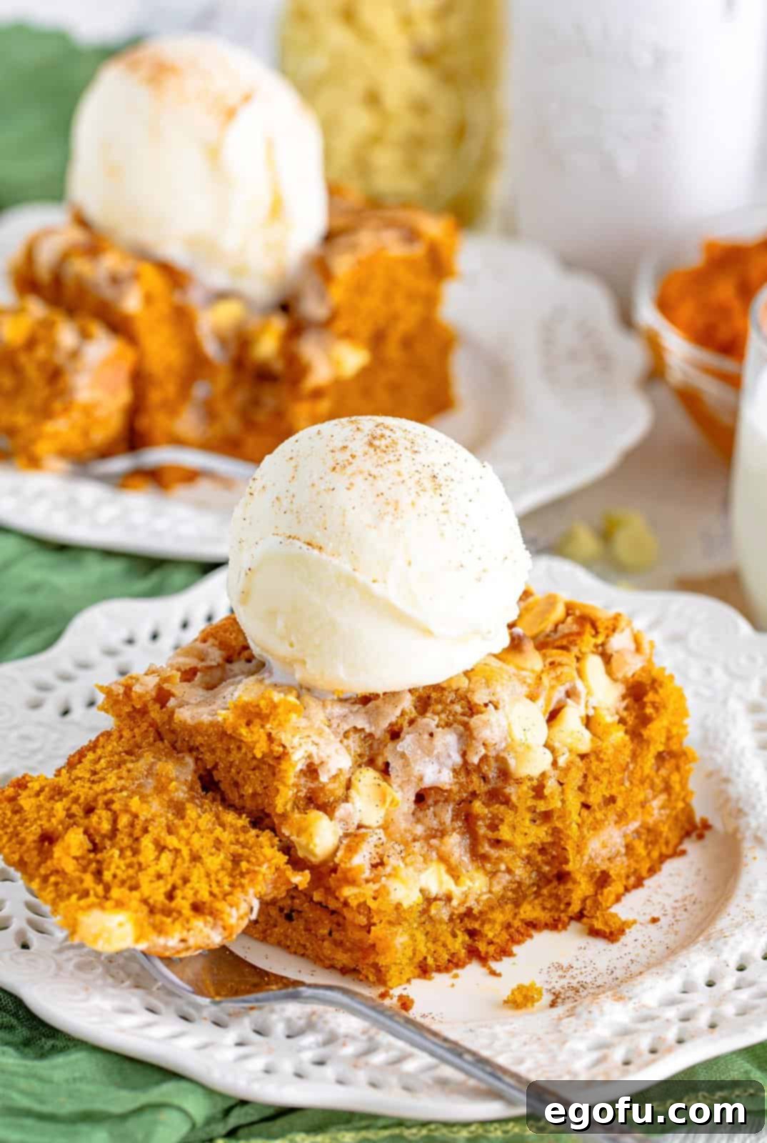 Pumpkin Earthquake Cake with bite taken out of it topped with ice cream, showcasing its gooey center and crackled top.
