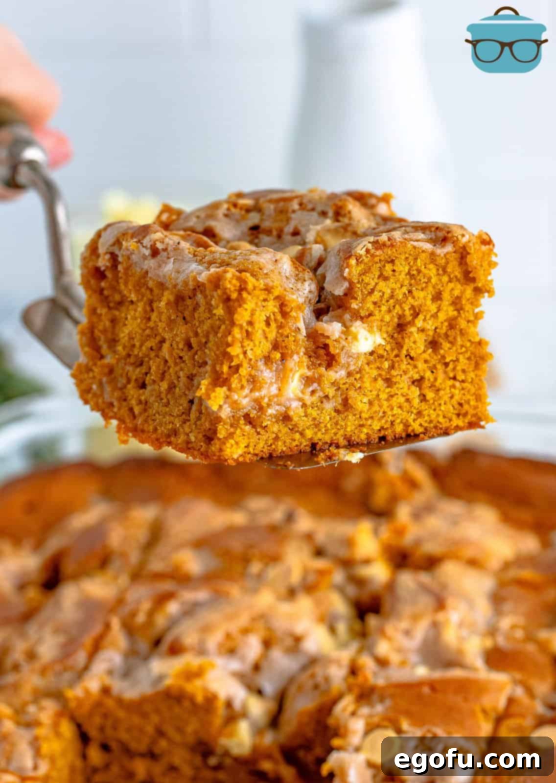 A slice of Pumpkin Earthquake Cake being lifted out of the pan with a cake server, revealing its moist interior.