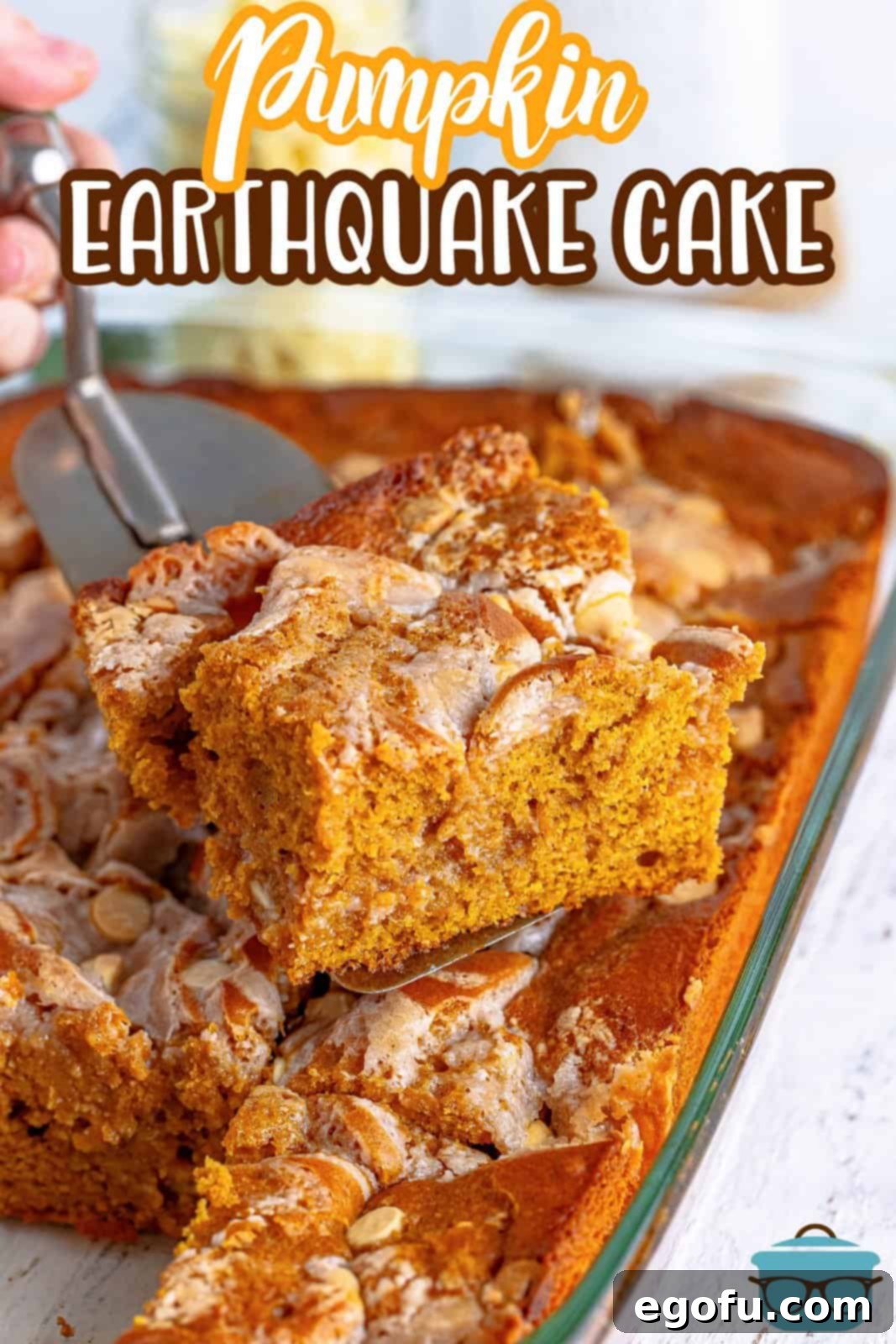 Pinterest image of cake server holding up a slice of the Pumpkin Earthquake Cake, showing its layers.