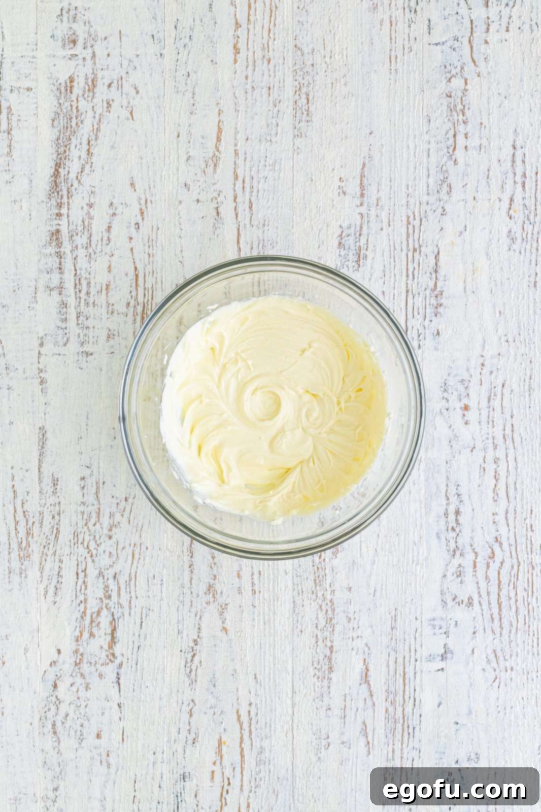 Cream cheese being beaten in a bowl until smooth.