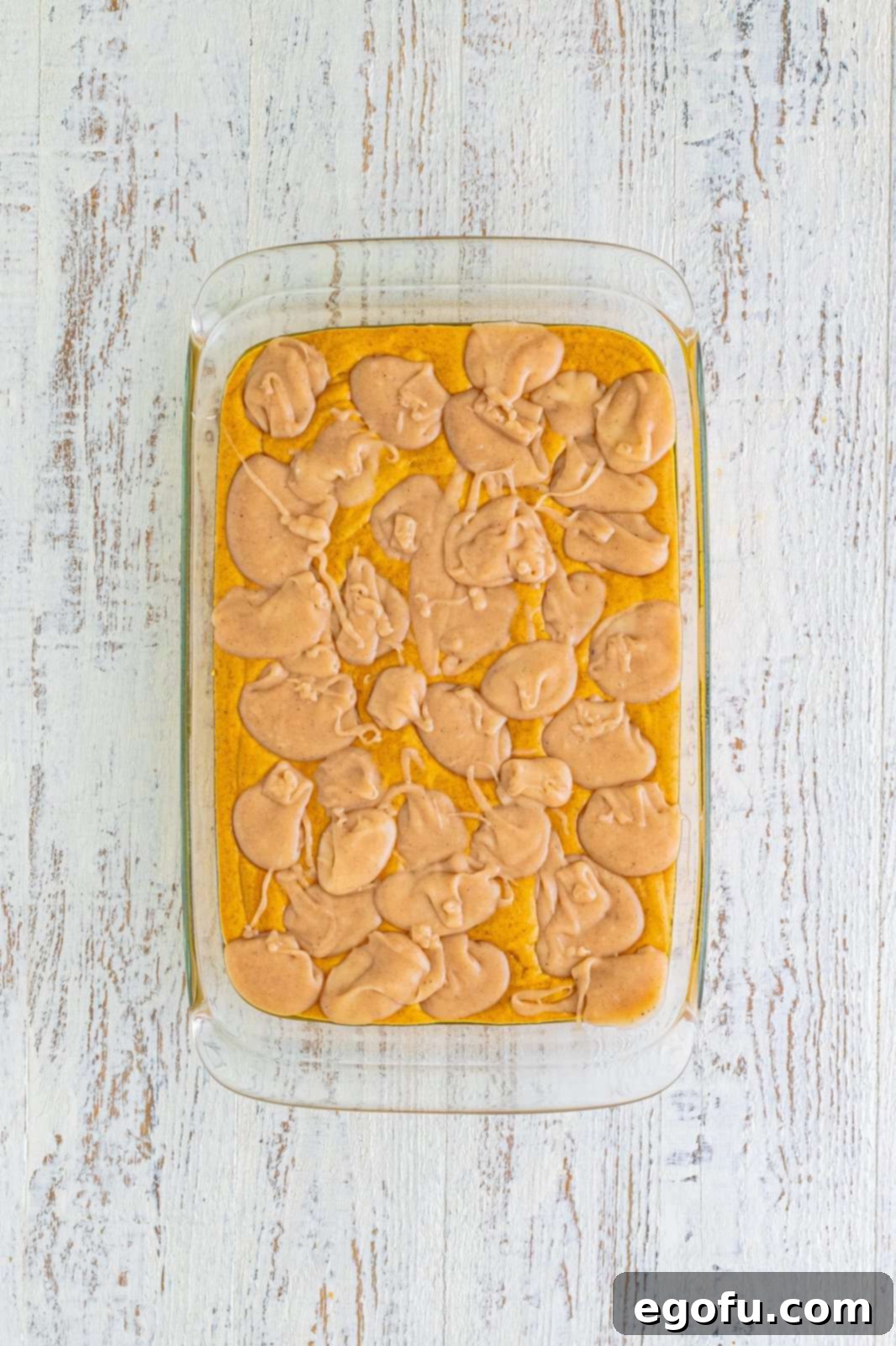 Cream cheese mixture dolloped over pumpkin cake batter in the pan.