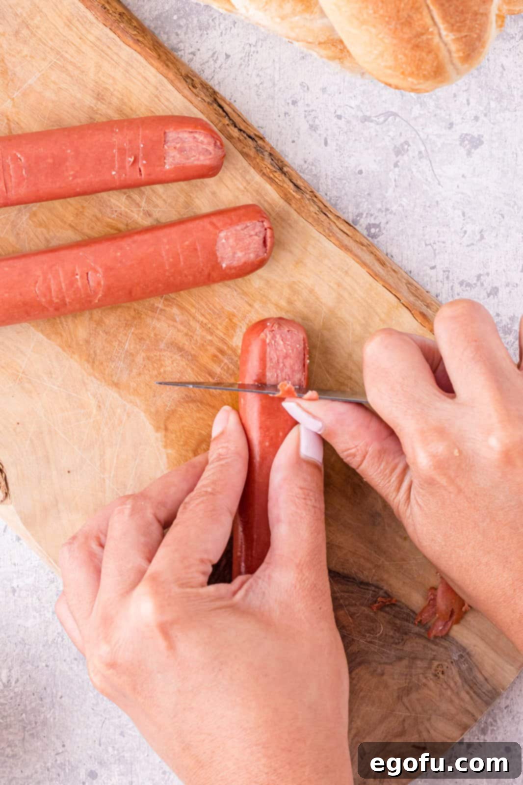 Knife scraping off a portion of the hot dog to make the fingernail.