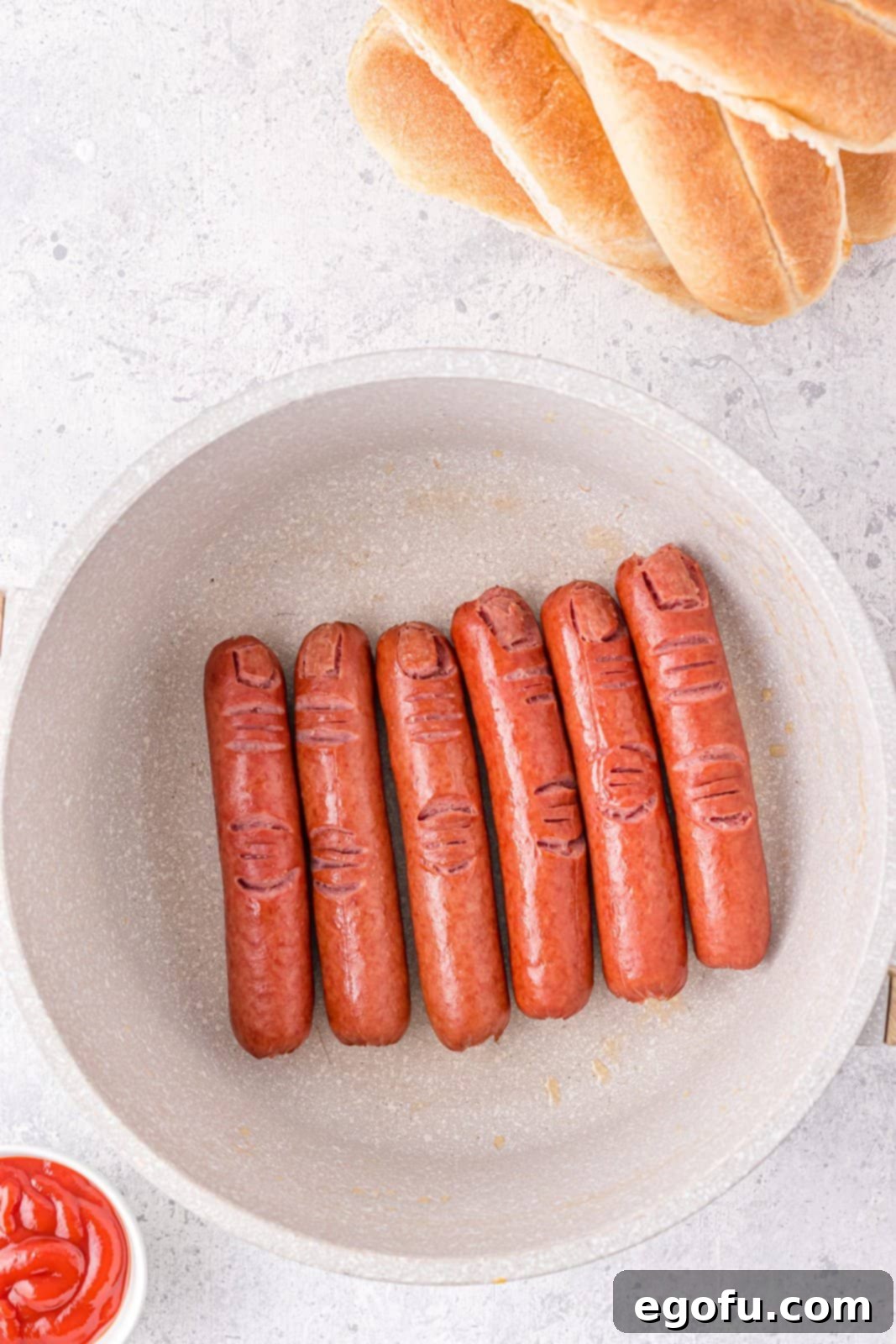 Hot dogs being fried in pan.