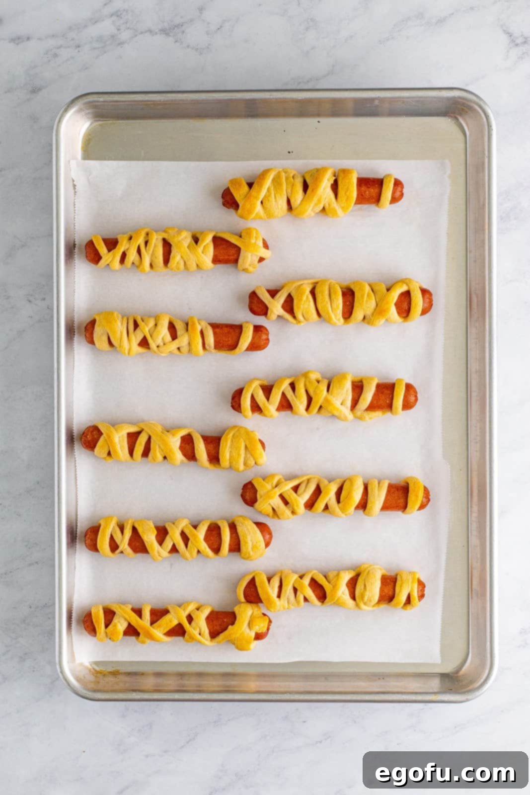 Freshly baked Halloween Mummy Dogs cooling on a baking sheet.