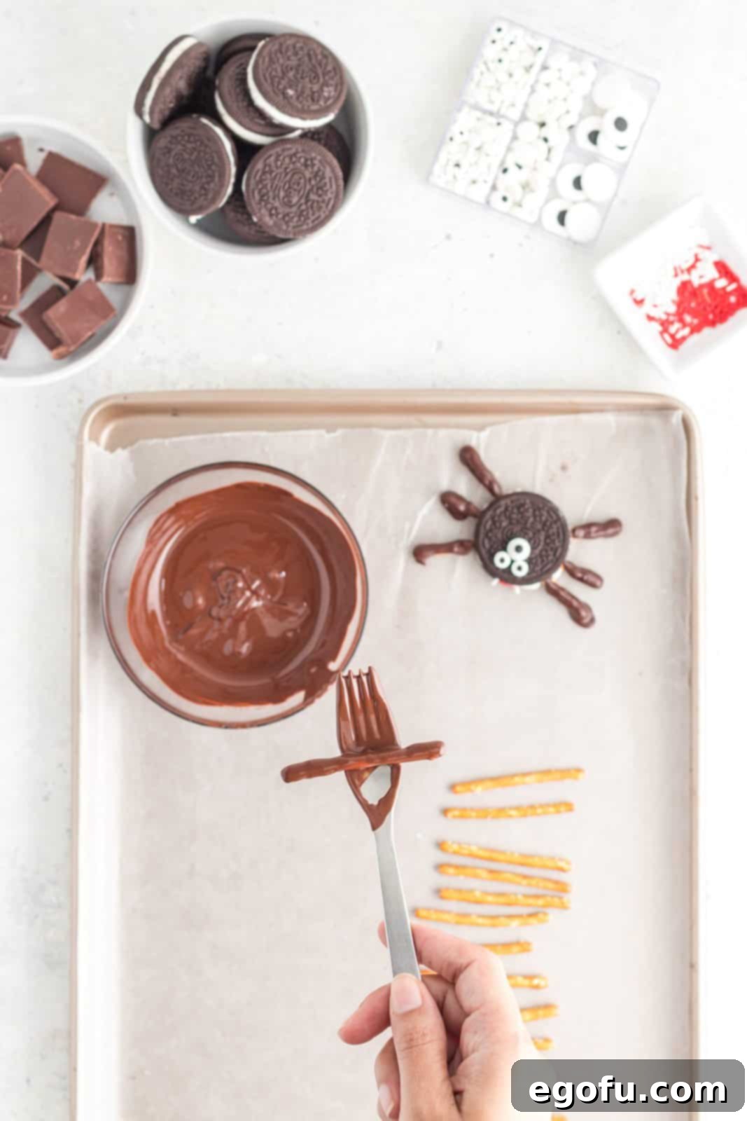 Spooktacular Oreo Spiders 6 Fork holding up one pretzel dipped in chocolate.