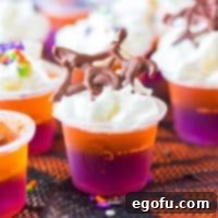 Close up square image of one of the decorated Hocus Pocus Jell-O Shots on black lace, featuring the whipped cream and chocolate spiderweb.