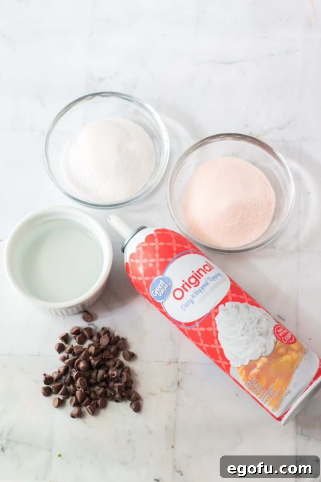 A perfectly arranged flat lay of all the essential ingredients: vibrant orange Jell-O, deep grape Jell-O, crystal clear boiling water, refreshing cold water, smooth vodka, creamy whipped topping (like Cool Whip), rich semi-sweet chocolate chips, and a sprinkle of festive Halloween decorations. These elements are ready to transform into delightful Hocus Pocus Jell-O Shots.