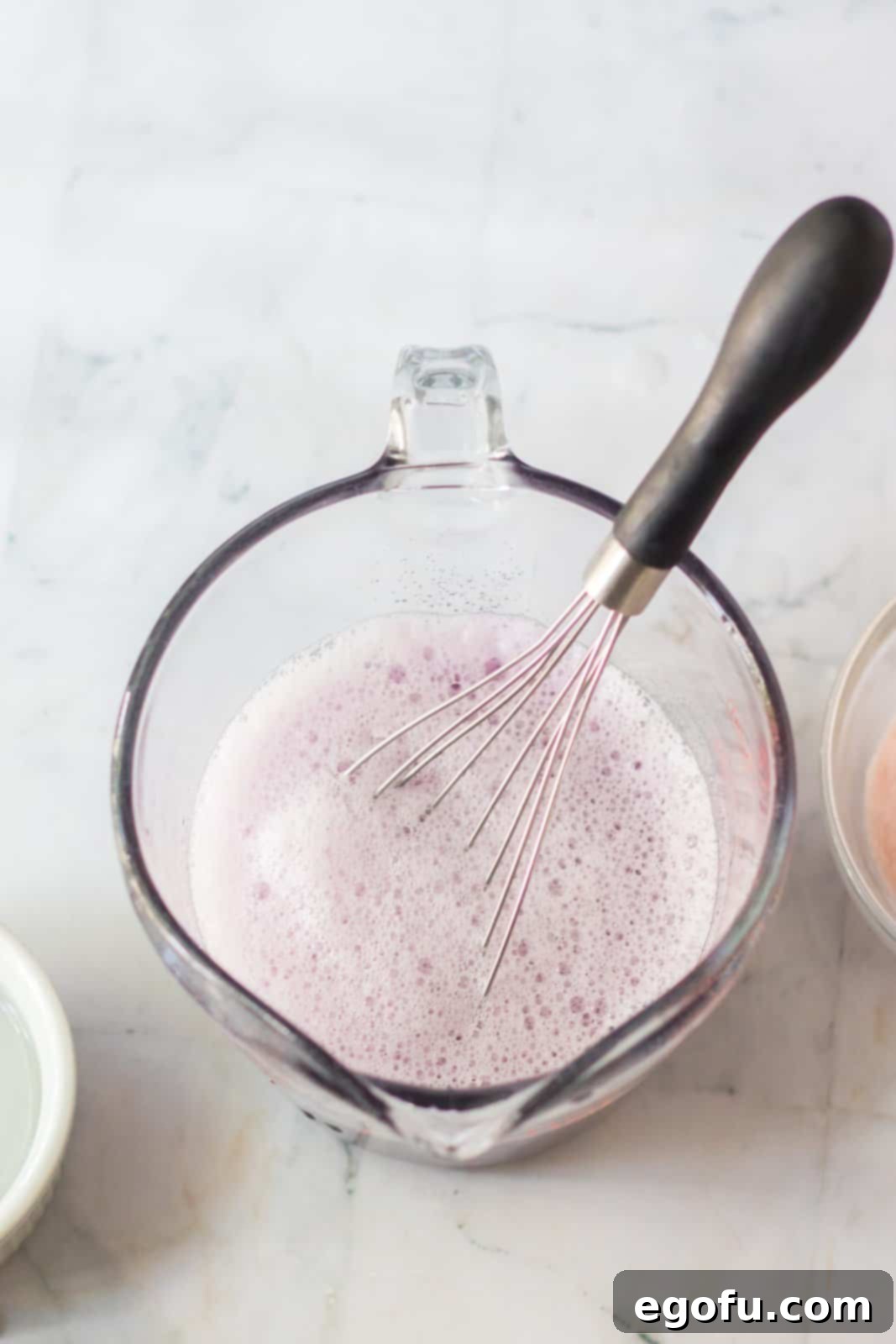 Purple Jell-O, water, and vodka perfectly mixed together in a clear, spouted measuring cup, showing the vibrant color and readiness for the next step of the Jell-O shot creation.