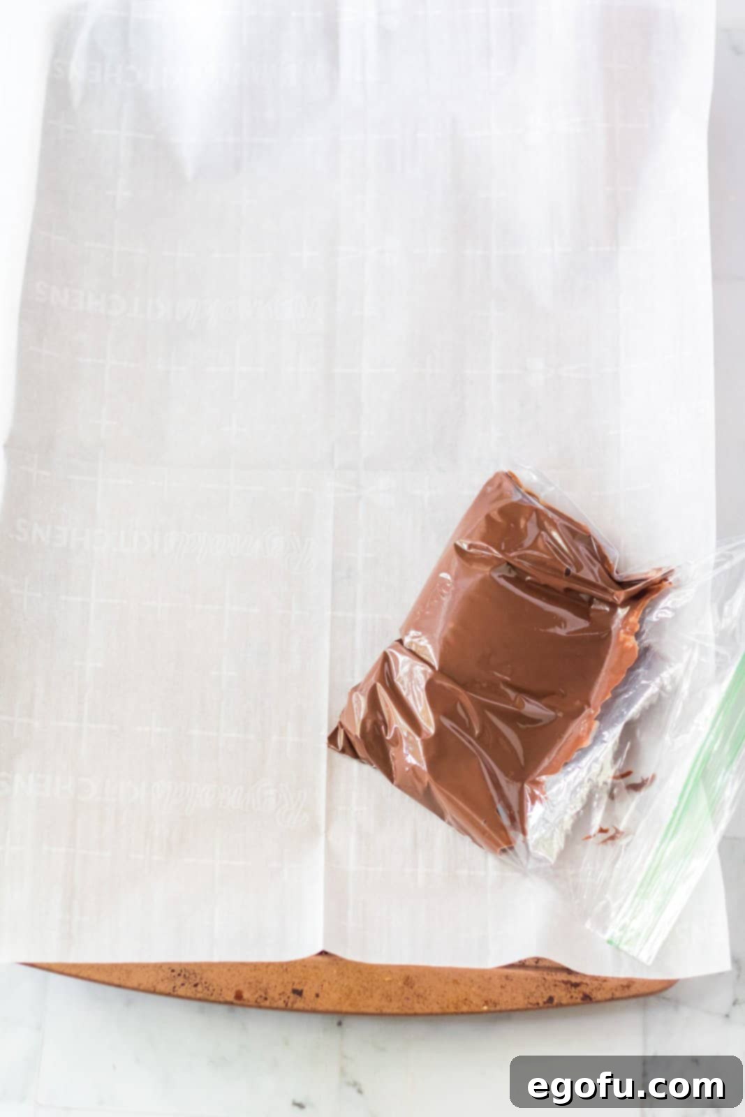 Smooth, melted chocolate carefully placed into a ziptop bag, with the chocolate pushed to one corner, ready for snipping and piping intricate designs.