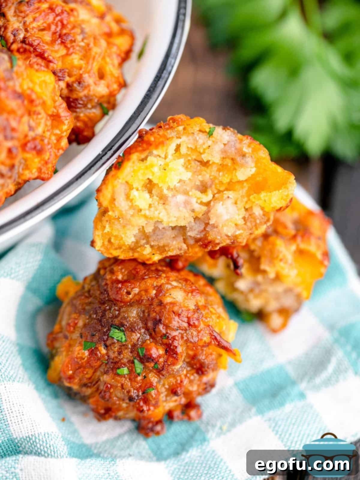Air Fryer Sausage Balls stacked on linen with bite taken out of one.
