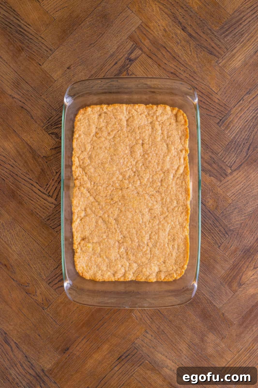 Classic Apple Crumble Bars 11 The golden brown, perfectly baked crust rests in the baking pan after its initial bake, forming a solid base for the apple filling.