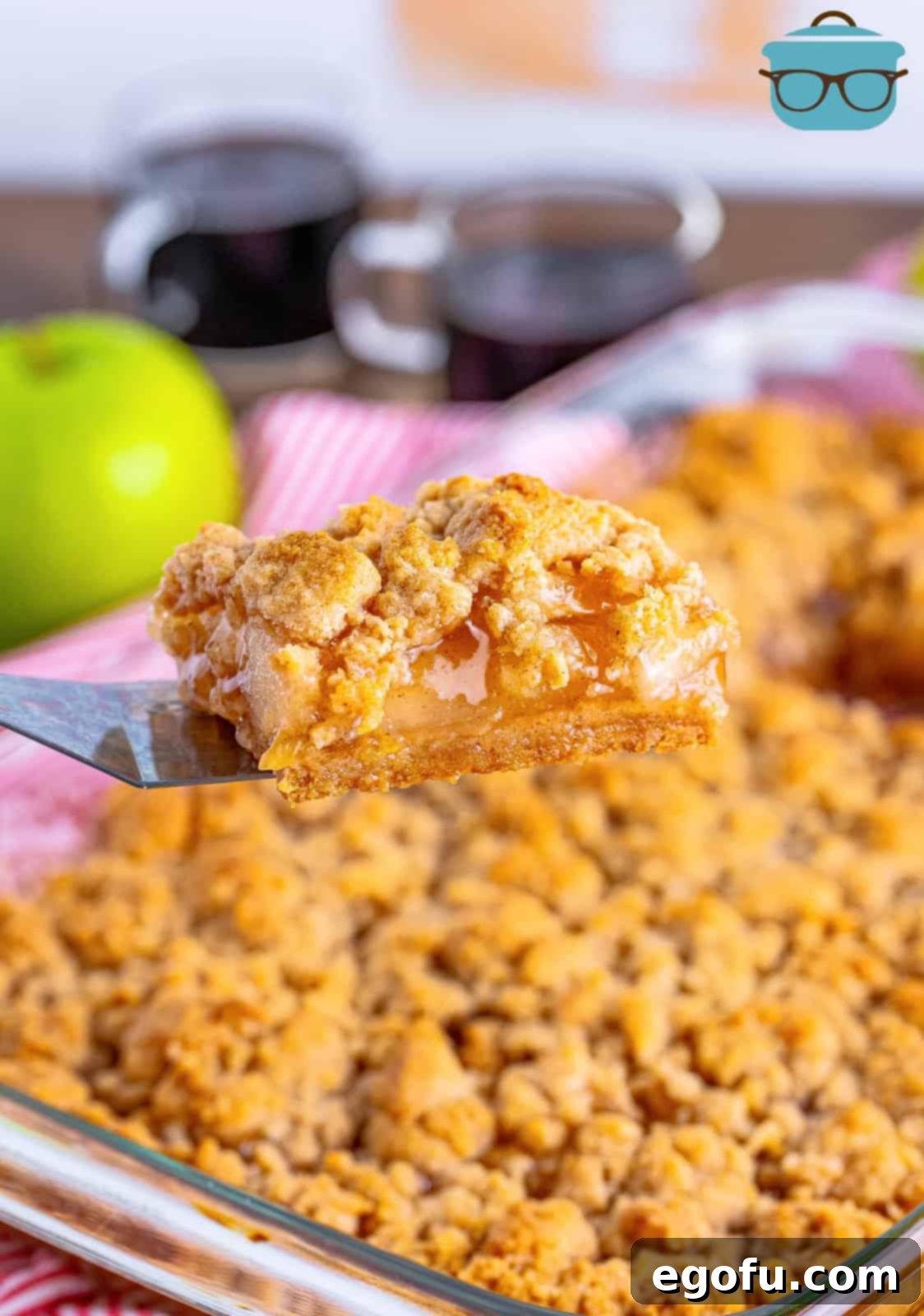 Classic Apple Crumble Bars 15 A serving spatula gracefully lifts one of the perfectly portioned Apple Crumble Bars from the pan, highlighting its golden crust and inviting layers.