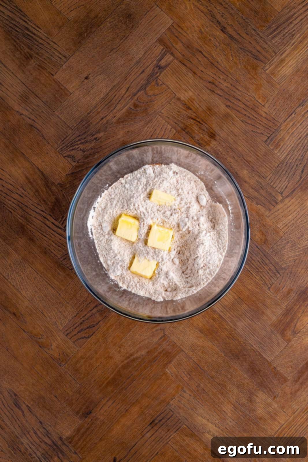 Classic Apple Crumble Bars 6 Clearly visible in a large mixing bowl, cubed unsalted butter has just been added to the previously whisked flour and spice mixture, preparing for incorporation.