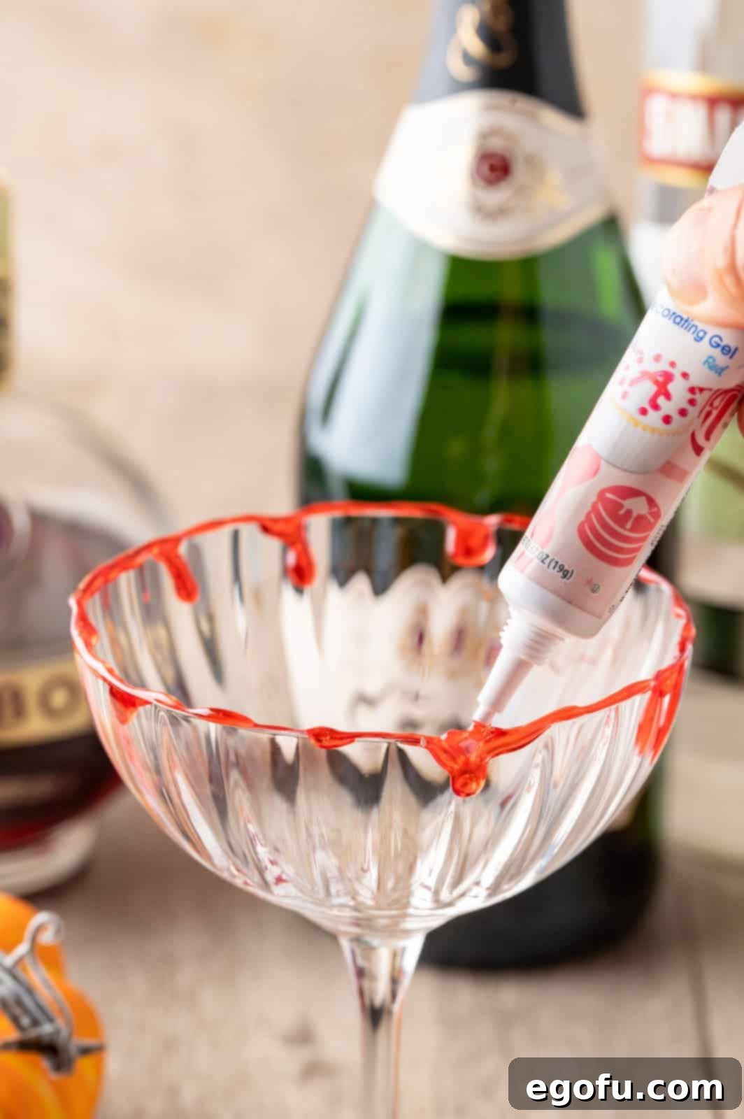 Crimson Embrace Elixir 4 Red decorating gel being artfully drizzled inside the rim of a martini glass to create a blood-drip effect.