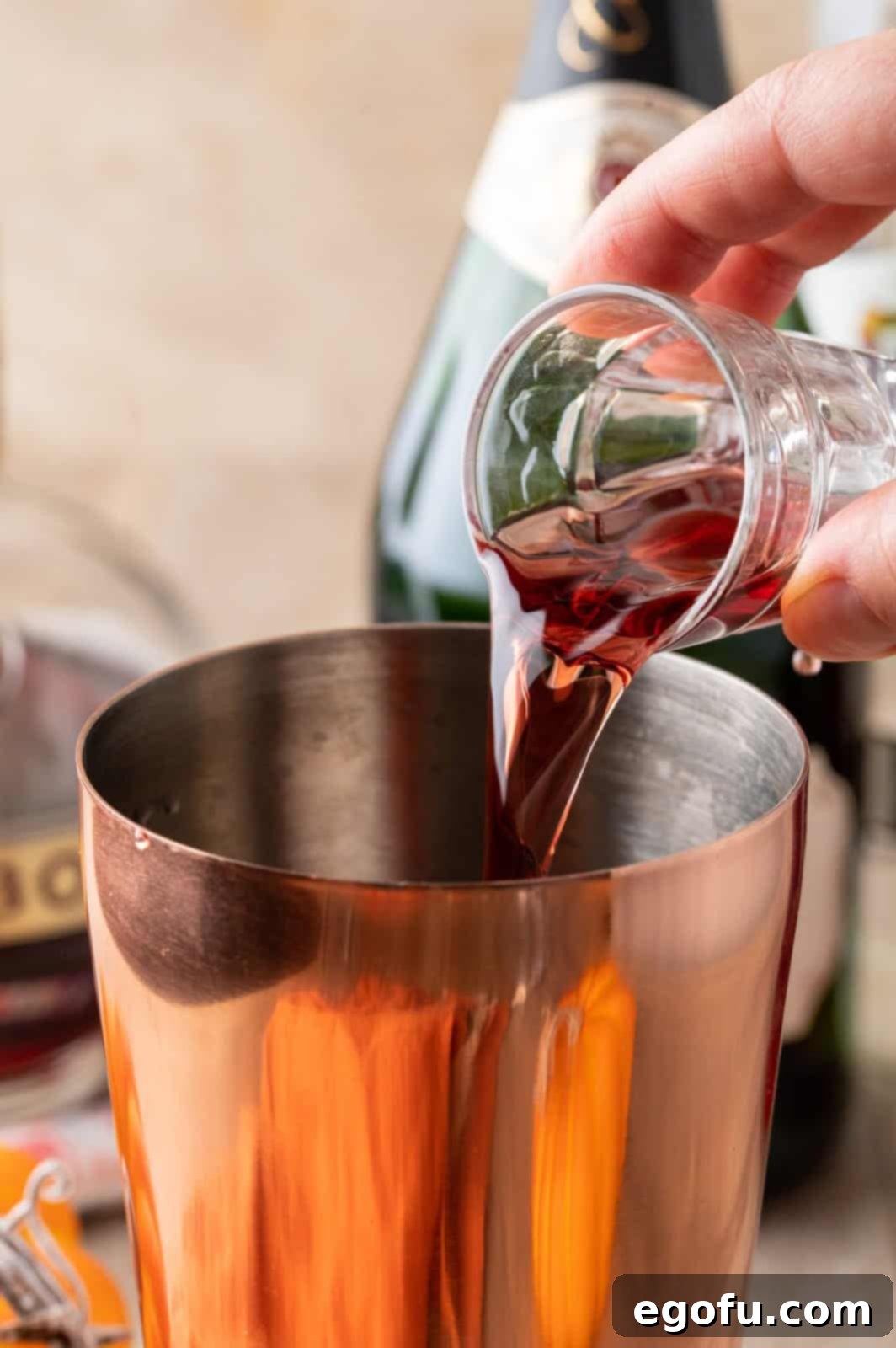 Crimson Embrace Elixir 6 Raspberry liqueur being poured into a cocktail shaker.