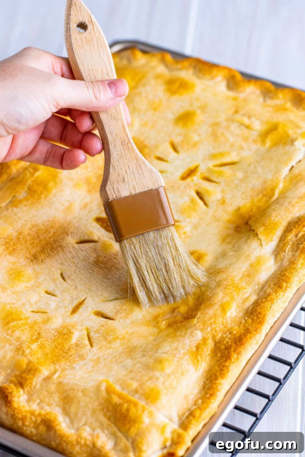 Glaze being brushed over the top of finished pie.