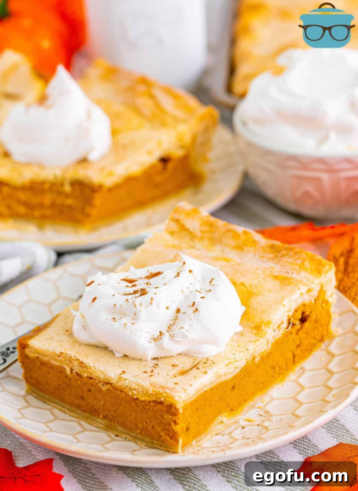 Slice of Pumpkin Slab Pie on plate topped with whipped cream and pumpkin pie spice.