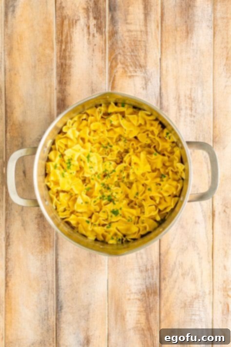 Campus Noodle Comfort 14 Cafeteria Noodles with parsley, stirred and ready to serve in a pot.