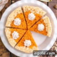 Close up overhead square image of Pumpkin Pie Rice Krispies Treats in pie plate topped with cinnamon whipped cream with slice missing.