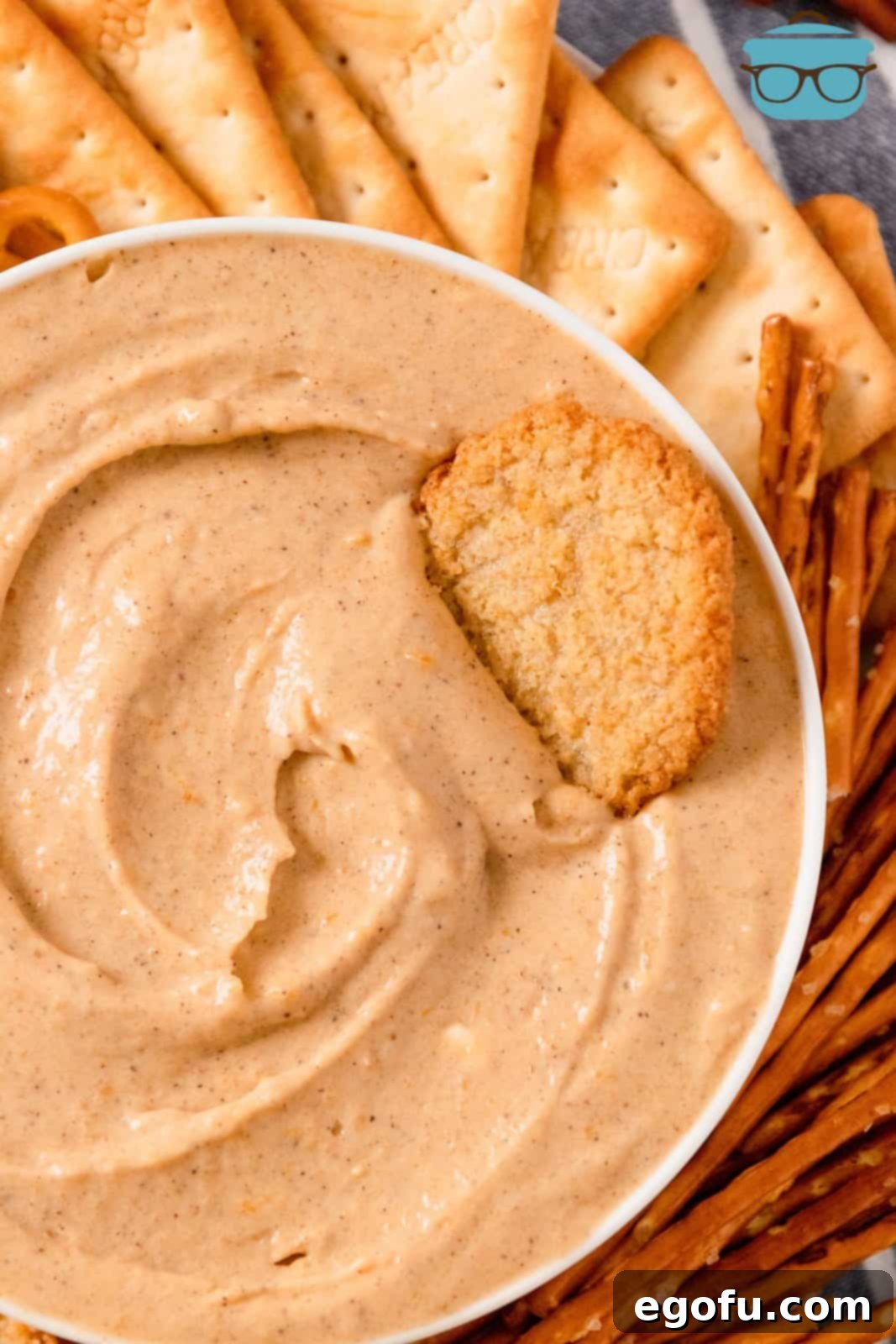 Close up overhead of Pumpkin Dip in white bowl with cookie in dip and other dippers around it.